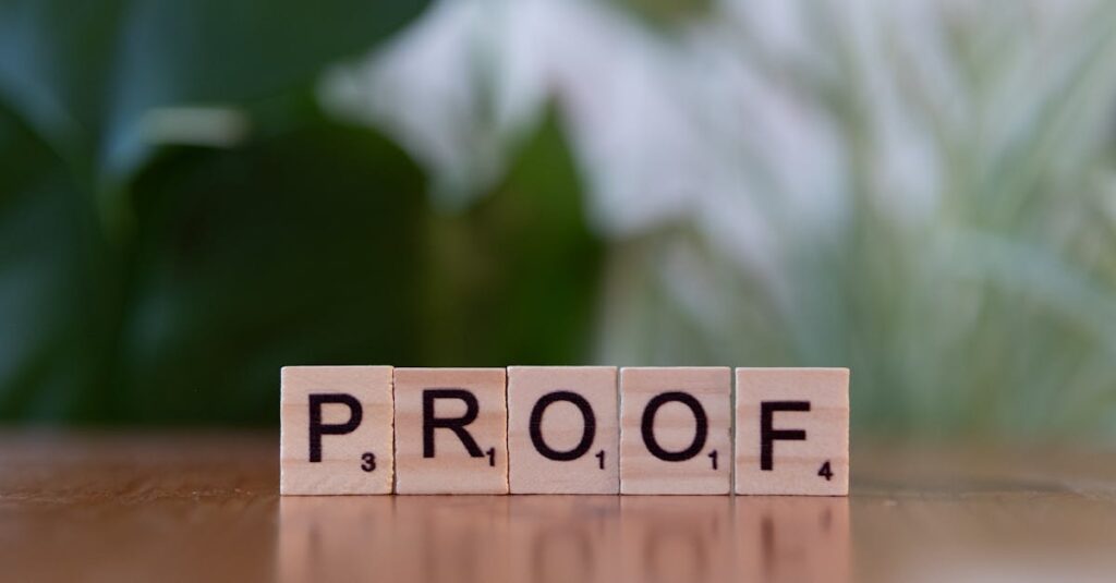 Wooden Scrabble tiles spelling 'PROOF' on a wooden table with green background.
